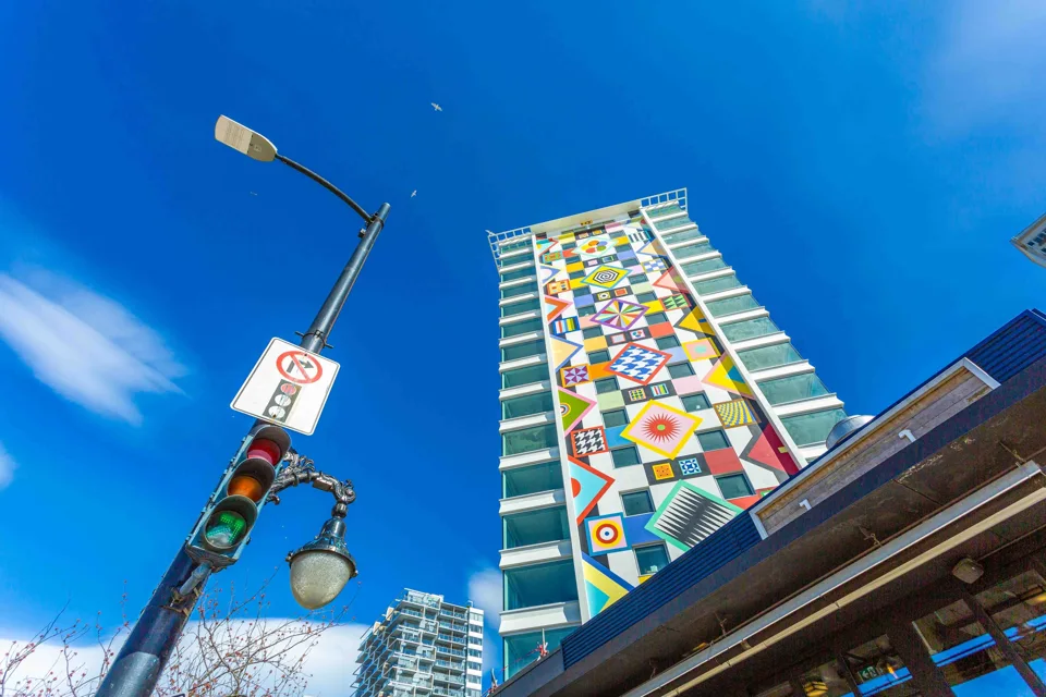 Colourful residential tower seen from street level against a blue sky
