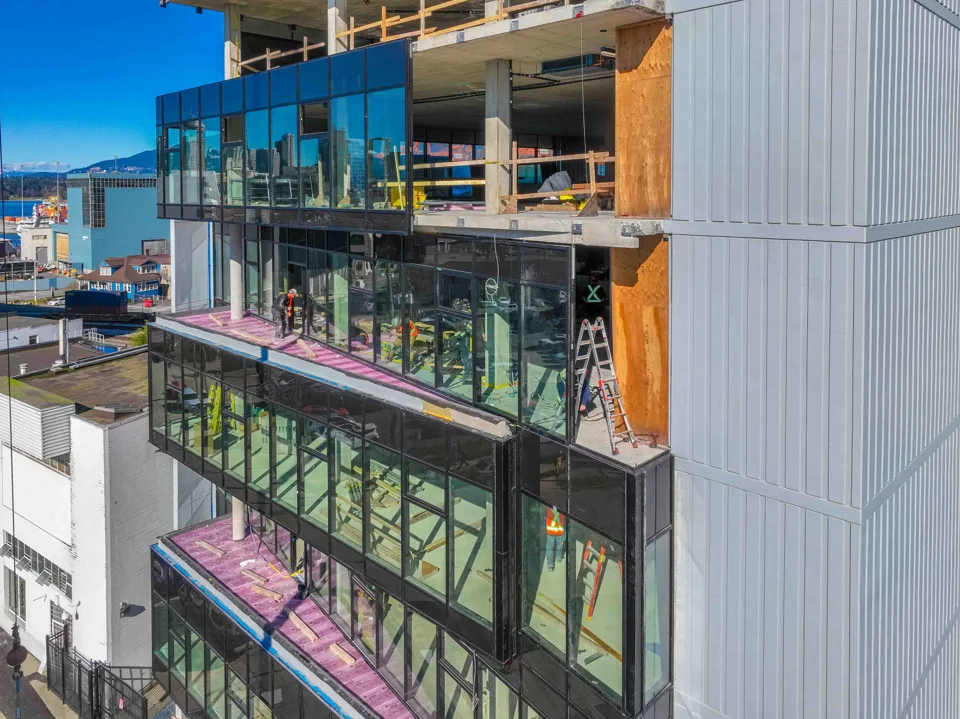 Close aerial view of glass facade installation on a building under construction