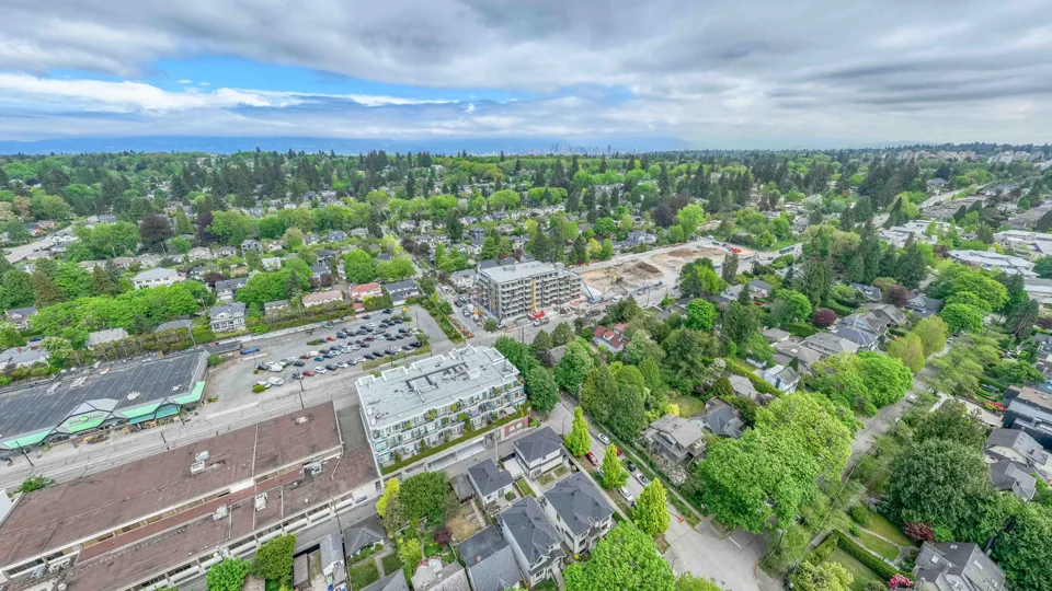 Wide aerial view of a development site and the surrounding tree-lined neighbourhood
