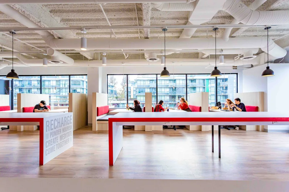 Shared workplace gathering space with a red table and pendant lights