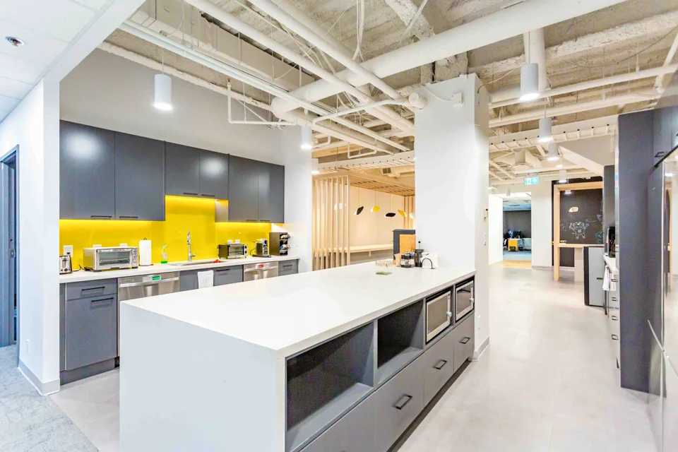 Modern workplace kitchen with a white island and yellow backsplash
