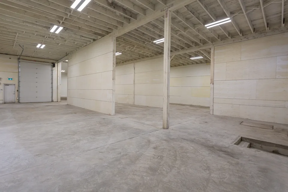 Empty warehouse with exposed roof structure and concrete floor