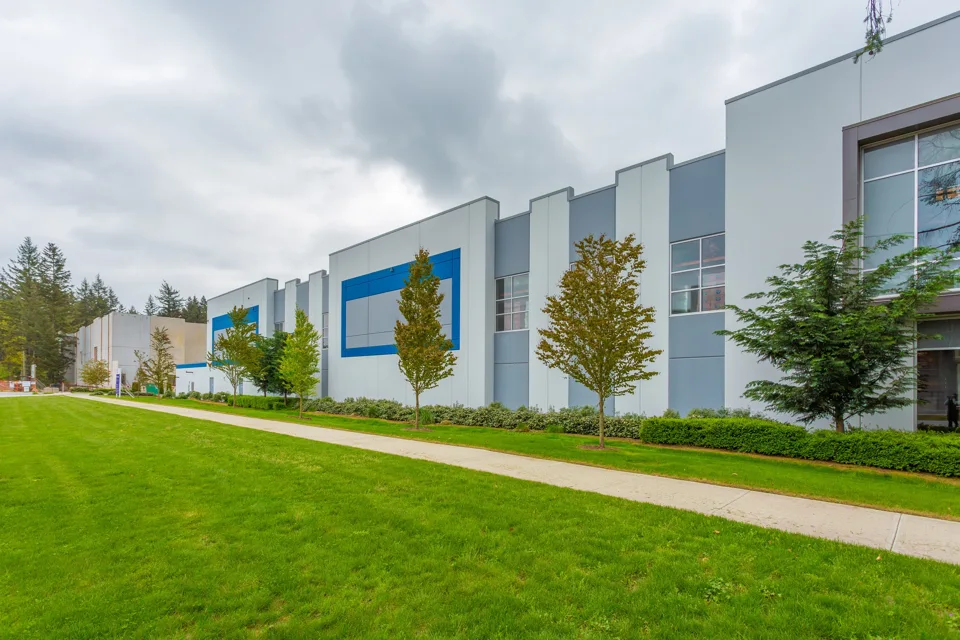 Industrial building facade with repeating bays and a landscaped edge