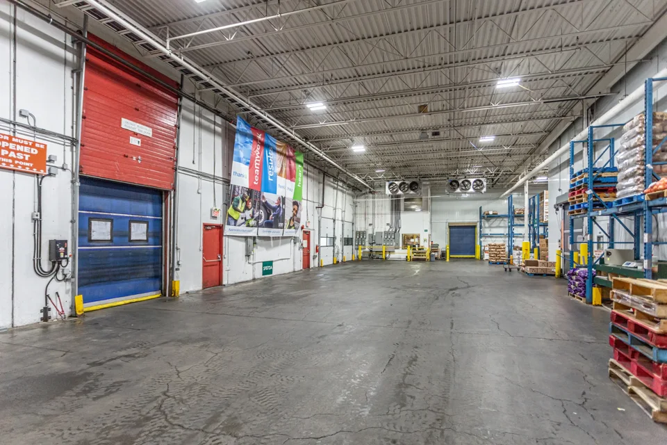 Open warehouse loading floor beside loading doors and storage racks