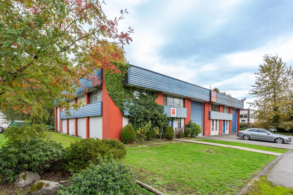 Red brick industrial building surrounded by trees and landscaping